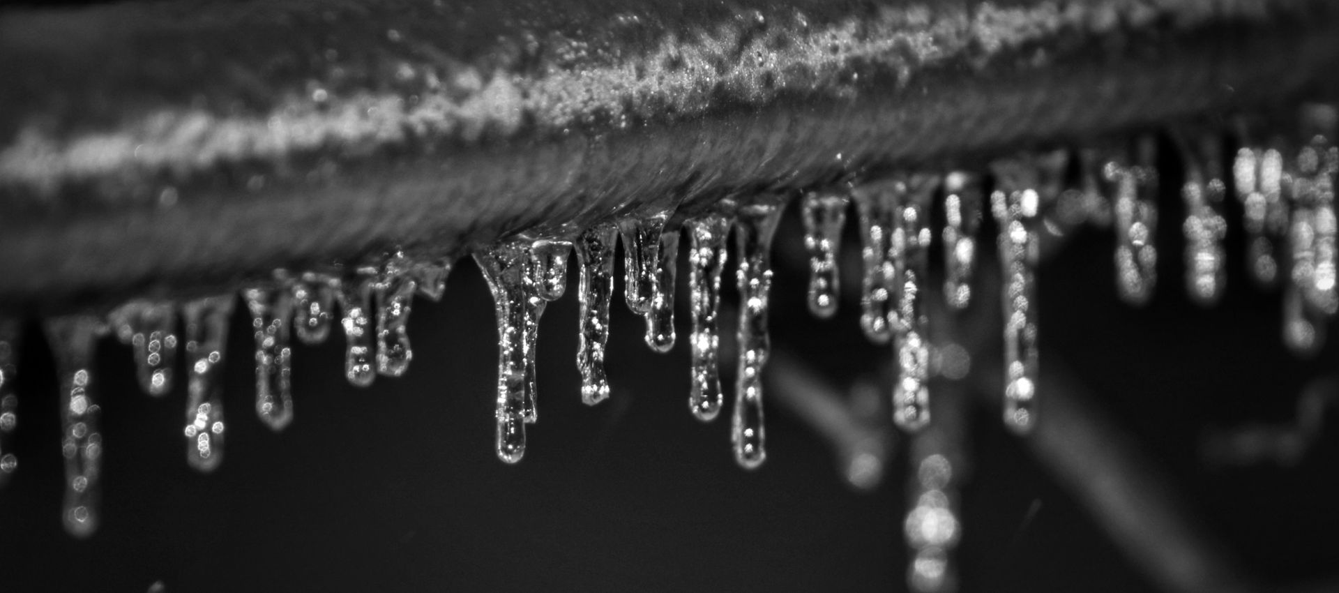 a black and white photo of icicles hanging from a pipe